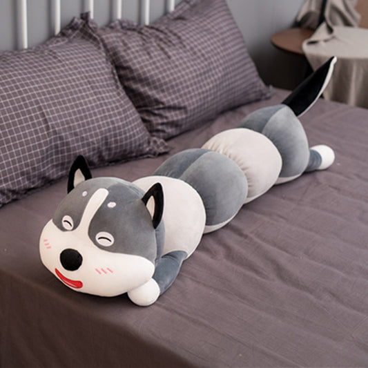 Plush toy shaped like a husky dog on a bed with pillows in the background