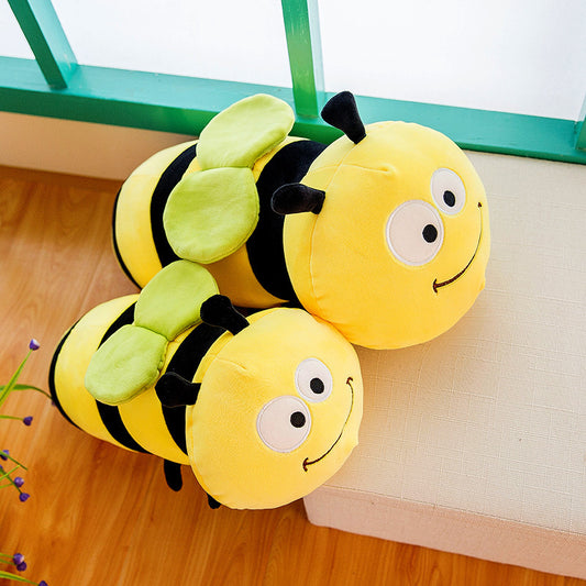 Plush bee-shaped cushion on a wooden floor with a green bench in the background