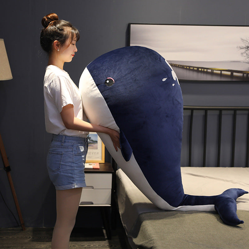 Woman holding a large plush whale toy in a bedroom setting