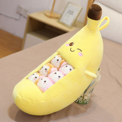 Banana-shaped plush toy with small plush toys inside on a bed