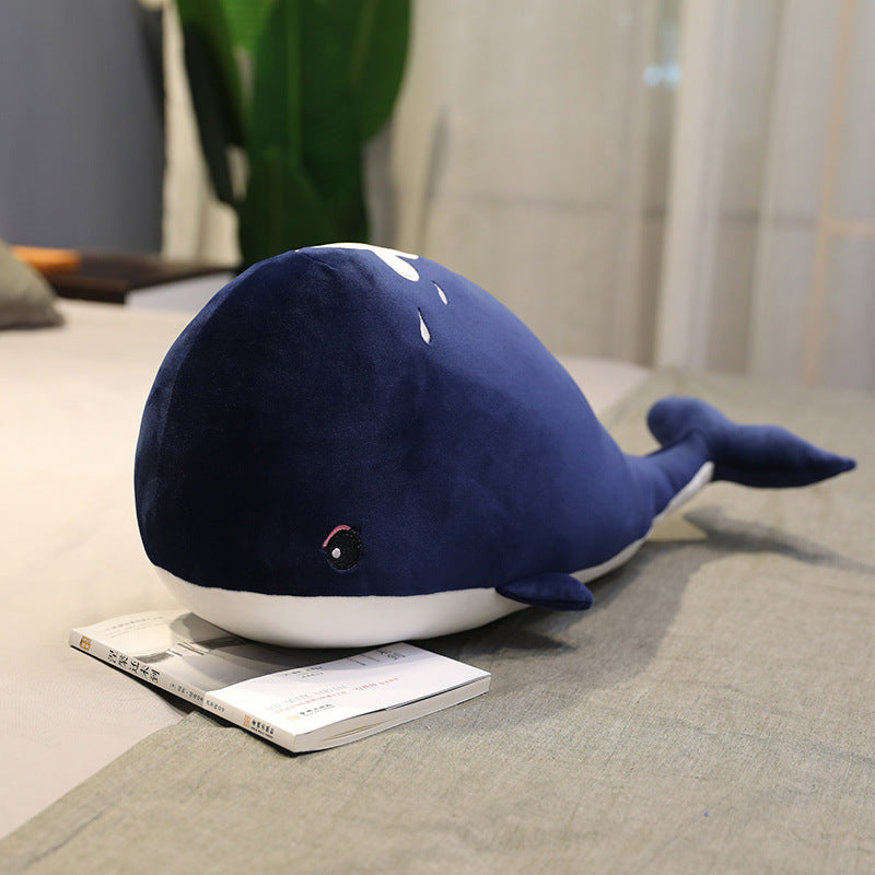 Blue whale-shaped plush toy on a couch next to a magazine