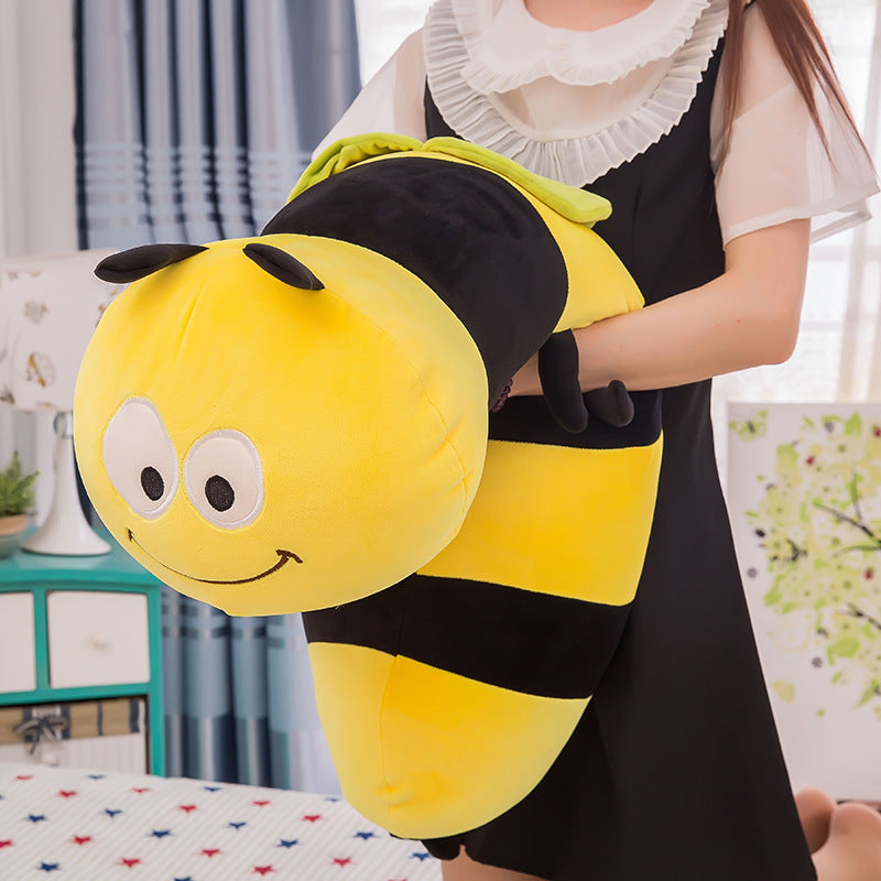 Person holding a large plush bee toy in a room with curtains and a table.