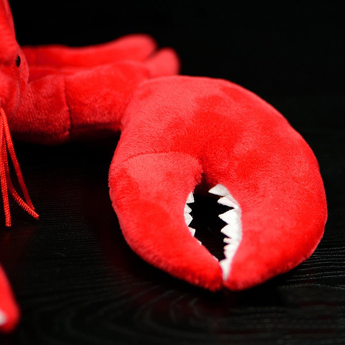 Red plush lobster toy with a black background