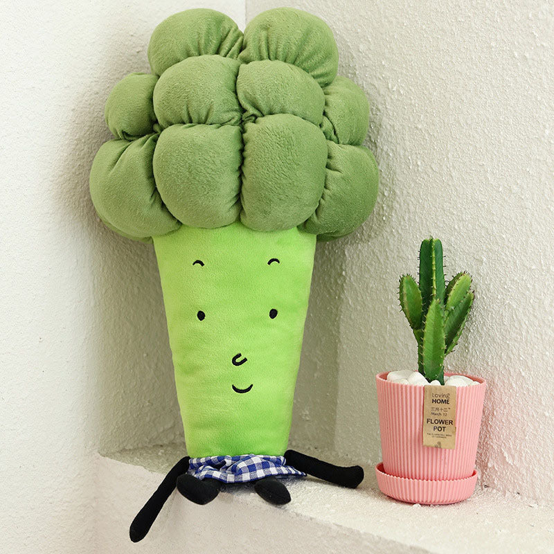 Plush broccoli toy with a small potted cactus on a white surface.