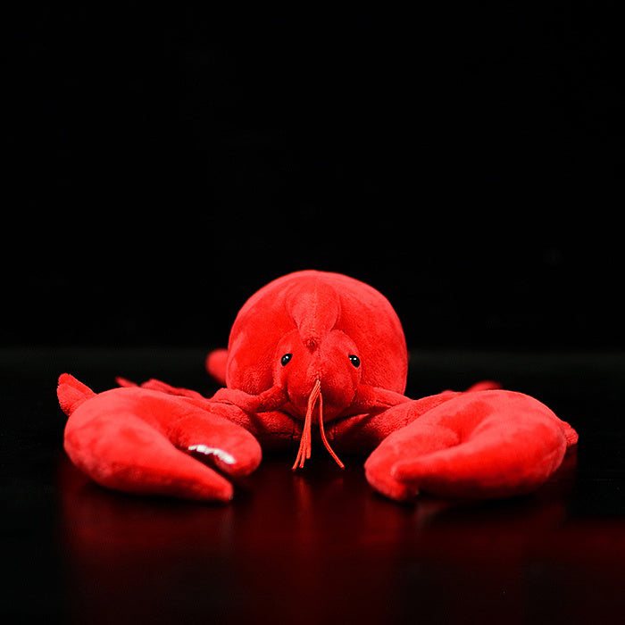 Red plush lobster toy on a black background