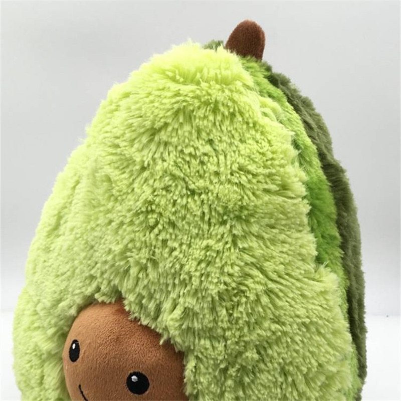 Plush toy resembling an avocado with a smiling face on a light gray background
