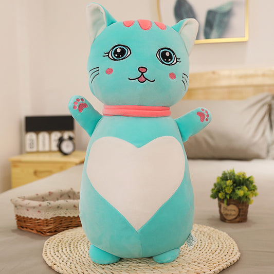 Blue plush cat toy with a white heart on a bed in a bedroom setting