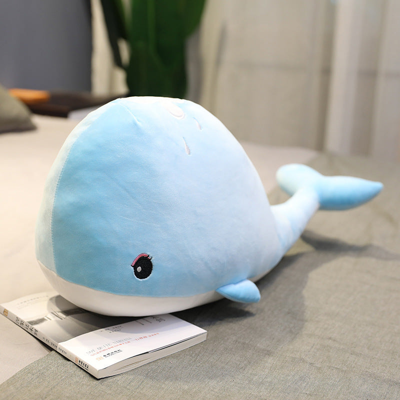 Blue whale plush toy on a gray surface with a blurred background
