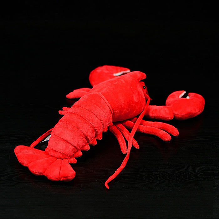 Red plush lobster toy on a black background