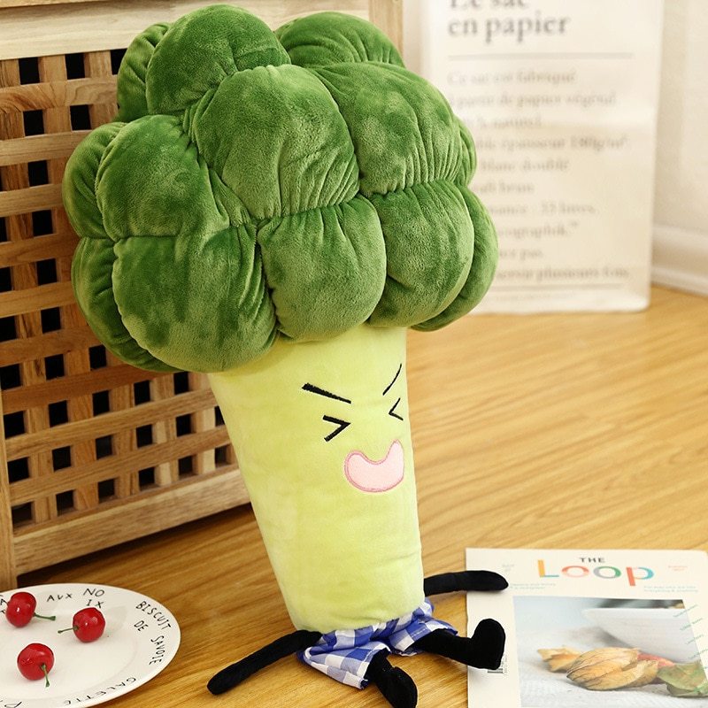 Plush toy shaped like a broccoli with a face on a wooden surface.