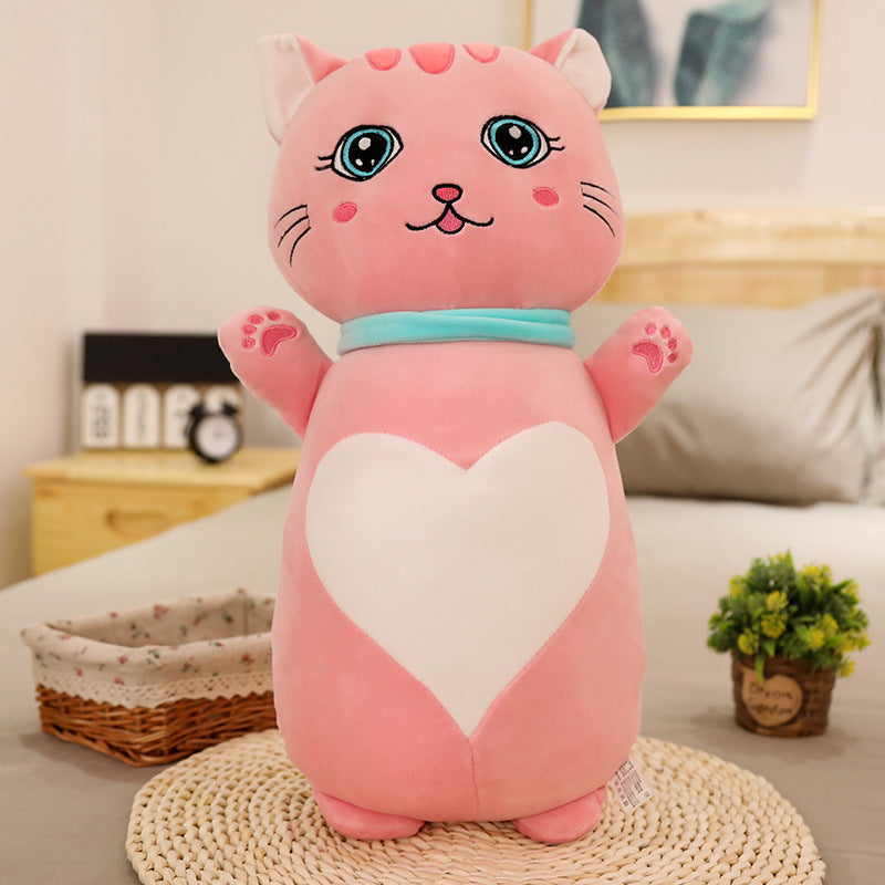 Pink cat-shaped plush toy with a heart on a bed