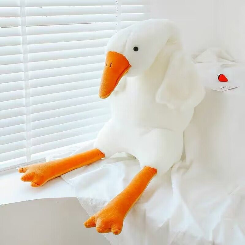 Plush toy goose with an orange beak and feet on a white surface.
