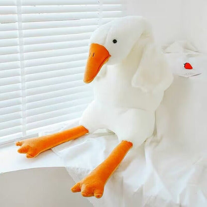 Plush toy goose with an orange beak and feet on a white surface.