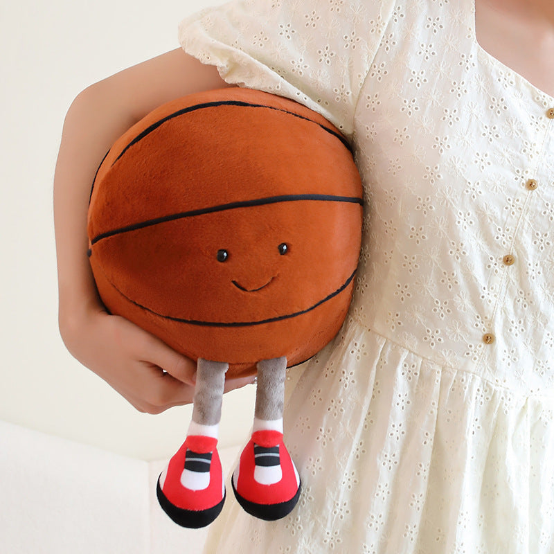 Plush toy shaped like a basketball with legs and shoes held by a person wearing a white dress.
